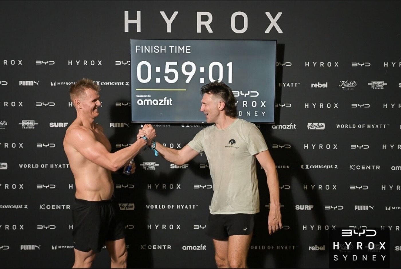 JL and his HYROX partner at the HYROX Sydney finish, clock showing 0:59:01